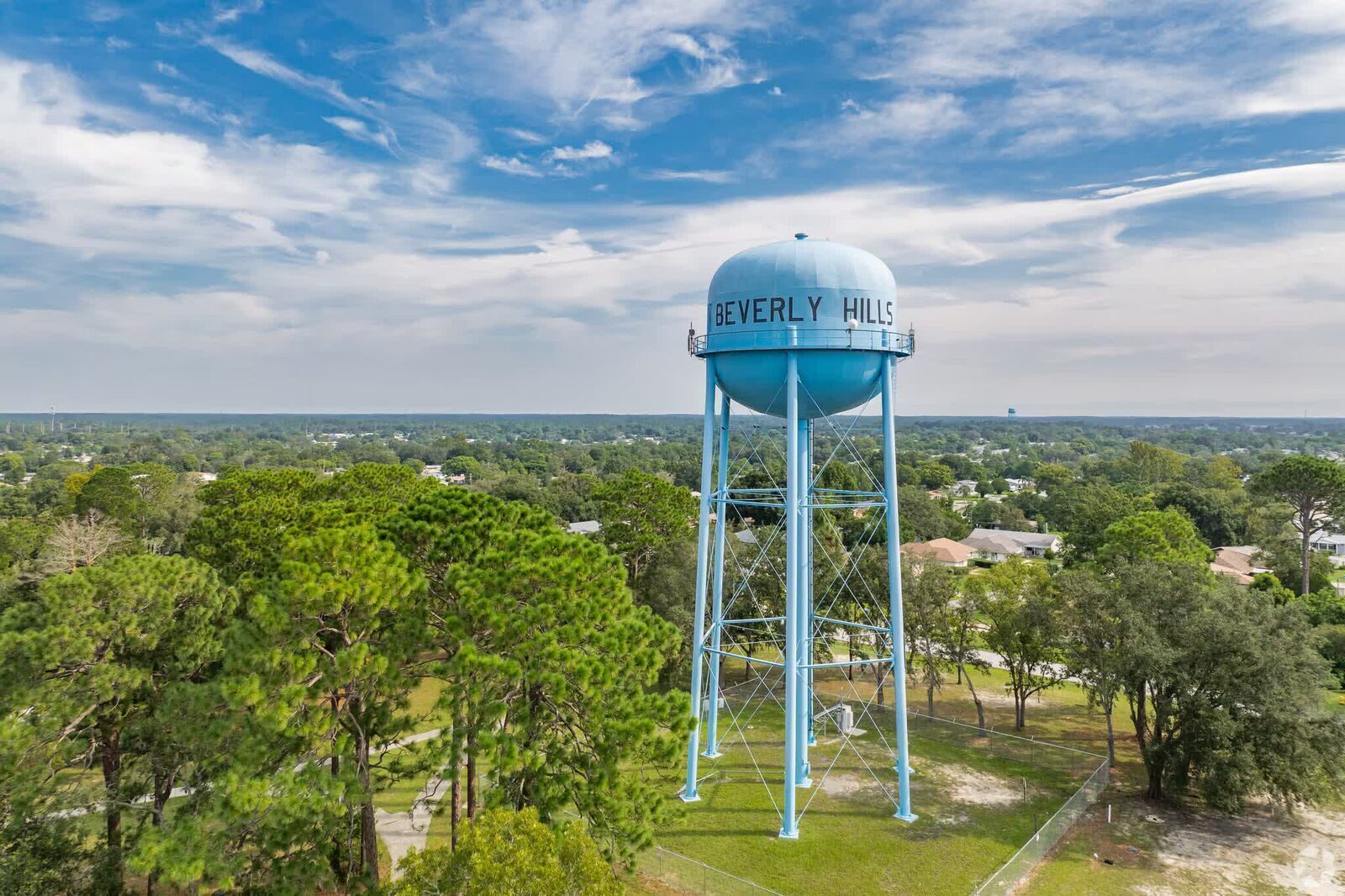 Drone view of the iconic blue Beverly Hills water tower rising above the tree canopy.