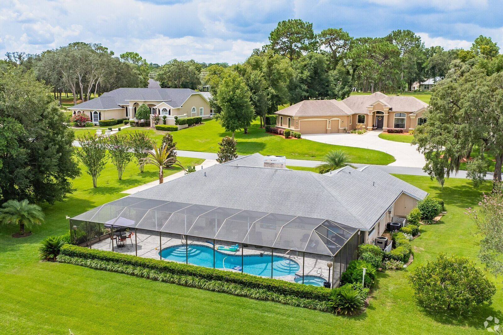 Aerial view of a screened-pool home in Citrus Hills, with neighboring homes on a quiet wooded street.