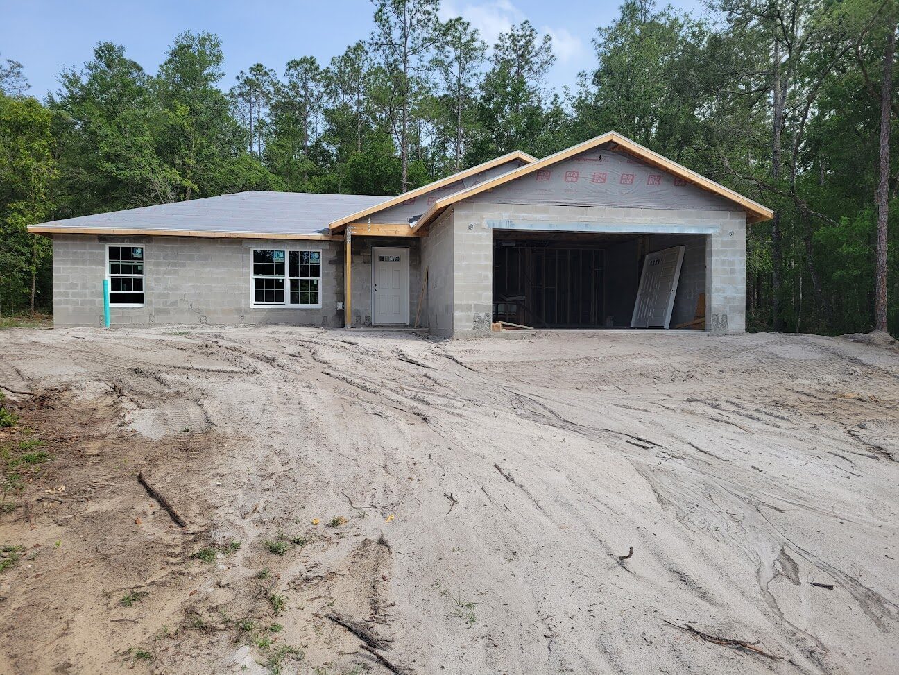 Concrete-block home mid-construction in Citrus Springs with framed roof in place.