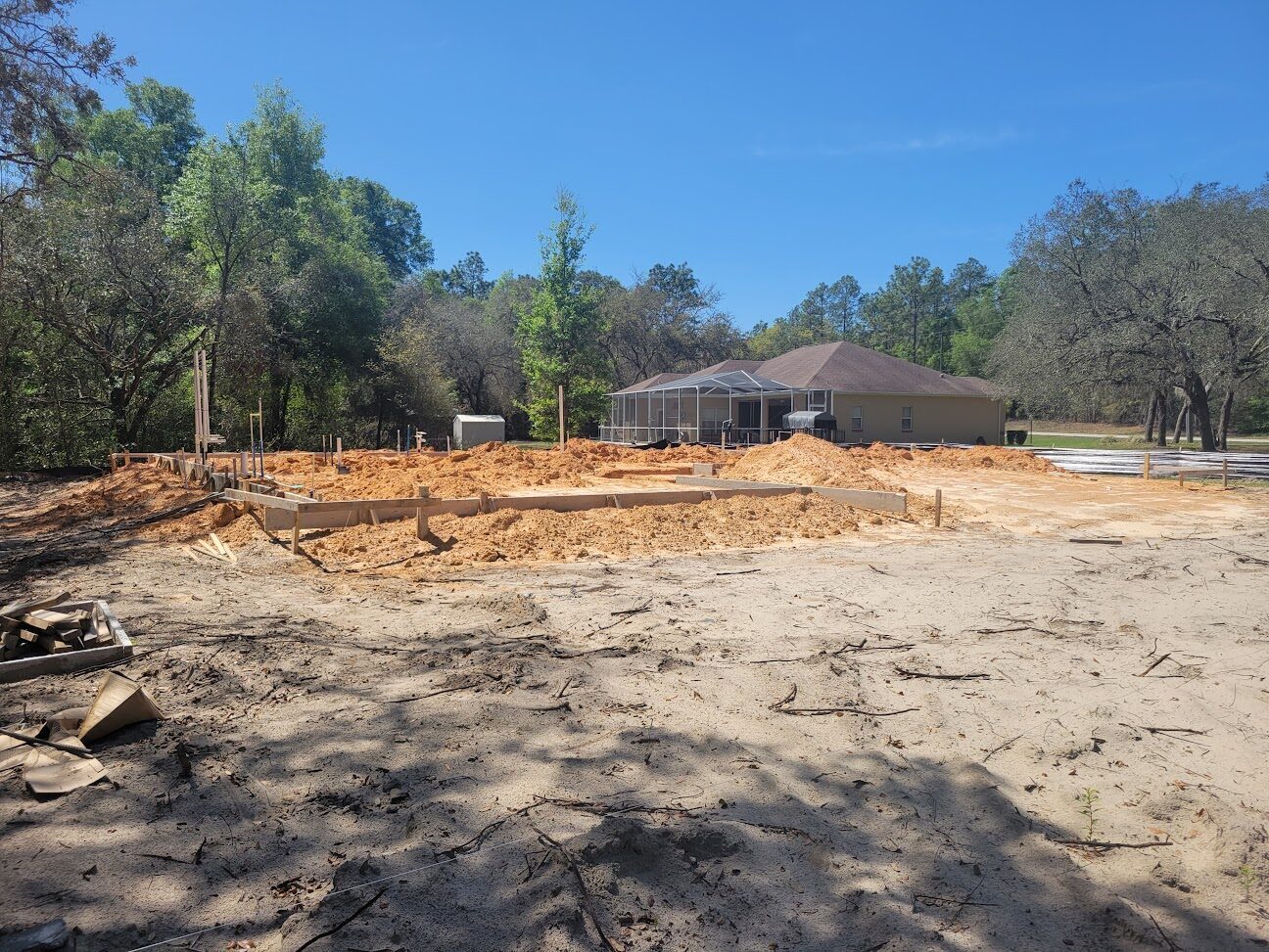 Concrete footings poured for a new home in Citrus Springs, with a completed neighboring home in the background.