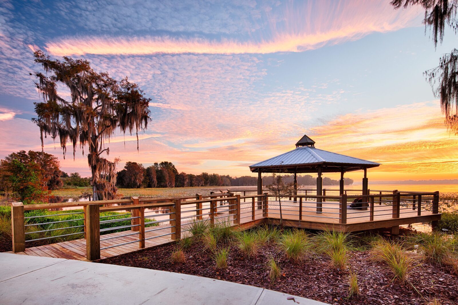 Lakeside gazebo at Liberty Park in downtown Inverness at sunset, with Spanish moss draping a cypress in the foreground.